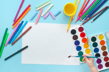 Closeup of child painting with brush in album on blue background