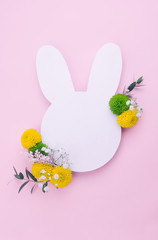 Easter bunny from white paper with flowers on pink background