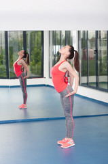 Obraz premium Beautiful young woman doing gimnastics on the floor with maces.