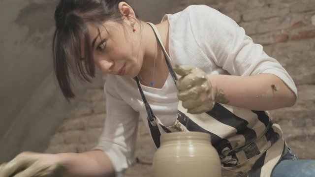 Beautiful girl sculpts a clay pot
