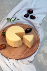 Cheese on wooden board served with olives, top view.