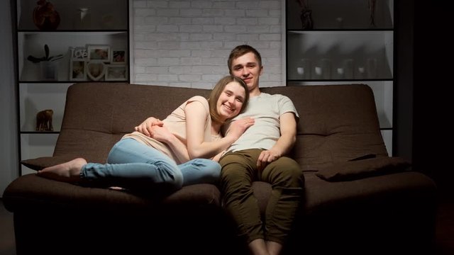 guy and girl are watching TV and smiling.