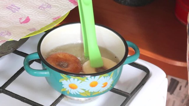 A woman is cooking American donuts. Bake them in sunflower oil