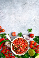 Tomato salsa (salsa roja) - traditional mexican sauce  with ingredients for making on a light grey slate,stone or concrete background.Top view with copy space.