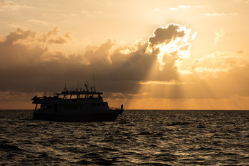 Obraz premium A gorgeous sunrise silhouettes a dive boat in the Caribbean Sea.