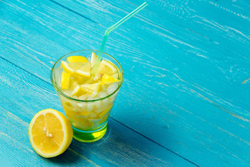 Water with lemon. Lemonade with lemon slices on blue wooden background.
