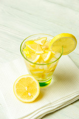 Water with lemon. Lemonade with lemon slices on white wooden background.