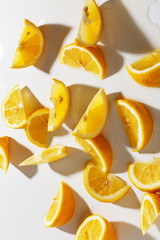 Lemons cut into pieces and a glass with natural lemonade on a white background. Top view.