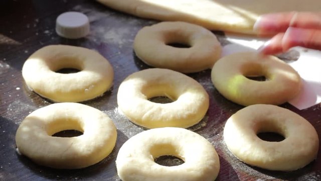Blanks for American donuts. Made of dough, lie on the surface of the table. Nearby are tools for cooking.