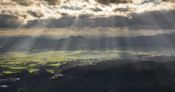 Sun rays protrude from the clouds on the farming agriculture landscape bellow like an alien scan.