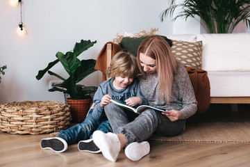 Mother and son sitting and reading book together at home
