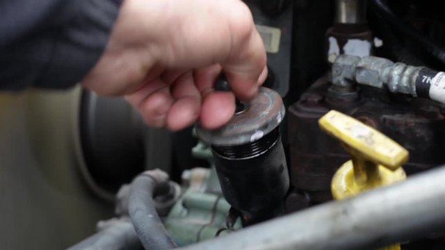 Man hand removes oil filler cap on semi truck engine, and white smoke comes out due to a mechanical problem.