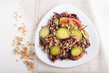 Vegetarian salad of purple cabbage, germinated wheat, tomatoes and avocado on linen tablecloth, top view.