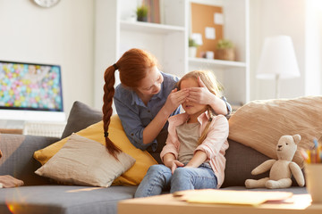 Portrait of two sisters playing hide and seek at home, focus on little girl counting, copy space