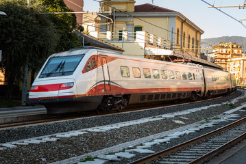 White passenger train is arriving to train station at Rapallo town, Italy
