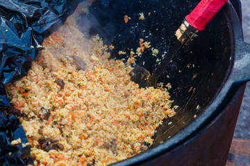 Traditional Uzbek plov lamb and rice pilaf outdoor cooking in kazan