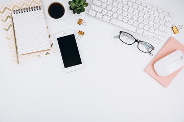 Flat lay, top view modern office table desk. Workspace with glasses, smartphone, keyboard, office supplies, pencil, green leaf, and coffee cup on white background