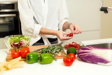 Brunette woman on the kitchen preparing healthy nutrition salad from fruits and vegetables. Housewife concept