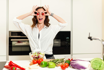 Brunette woman on the kitchen preparing healthy nutrition salad from fruits and vegetables. Housewife concept