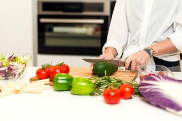 Brunette woman on the kitchen preparing healthy nutrition salad from fruits and vegetables. Housewife concept
