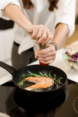woman preparing fresh fish steak on the kitchen with vegetables and glass of white wine and spices. Housewife concept