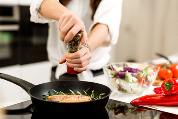 woman preparing fresh fish steak on the kitchen with vegetables and glass of white wine and spices. Housewife concept