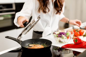 woman preparing fresh fish steak on the kitchen with vegetables and glass of white wine and spices. Housewife concept