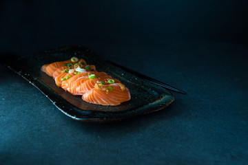 Salmon sashimi on dark background wth copy space