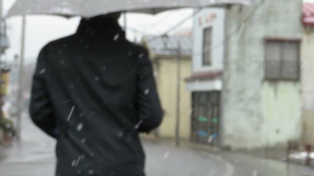 雪が降る道路を歩く男性
