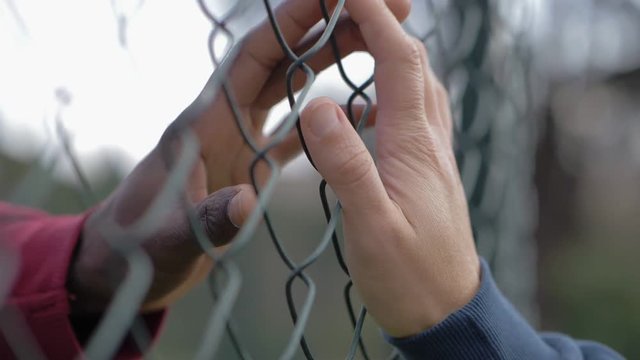 impossible love, Prohibition.Black man hands touch white woman hands through net