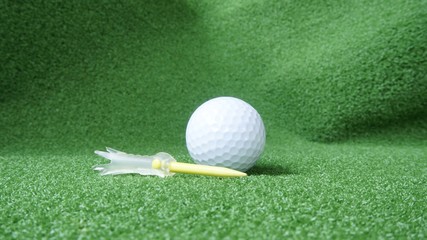 Golf ball and tee on green grass