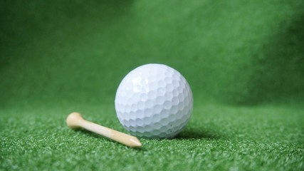 Golf ball and tee on green grass