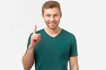 Stunned male points with fore finger upwards, he gets a good idea or good news about a successfully...