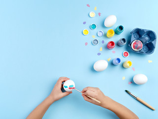 Kid's hands painting Easter egg.