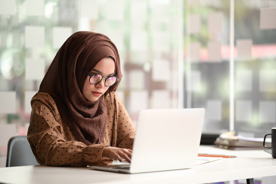 Woman Wearing Hijab Using Laptop In Office