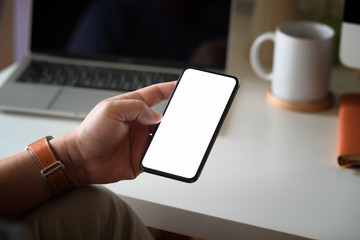 Blank screen mock up mobile phone in man hand at office