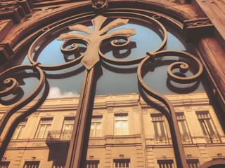 Reflection of a building on the street in a glass wooden door with an iron decorative ornament. Old Tbilisi architecture