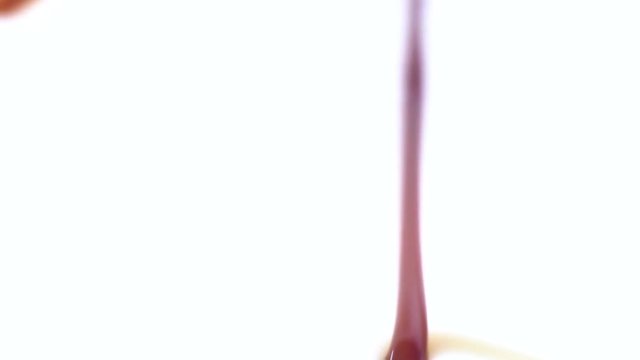 chocolate syrup is being poured into pure white milk. abstract shapes are formed as the liquid splashes into the white glass