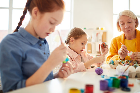 Group of children painting eggs for Easter in art class, copy space