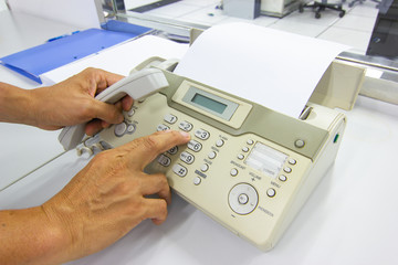 Hand man are using a fax machine send paper in the office Business concept 