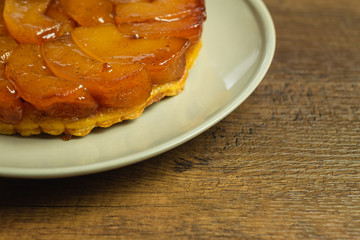 Freshly baked homemade Apple Tarte Tatin on a gray plate on a wood table top.
