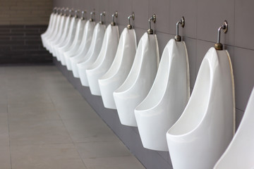 Men public toilet, restroom for male..Gents latrine wc bathroom..Closeup row of outdoor white urinals, design of white ceramic in modern restroom interior with copy space advertisement.