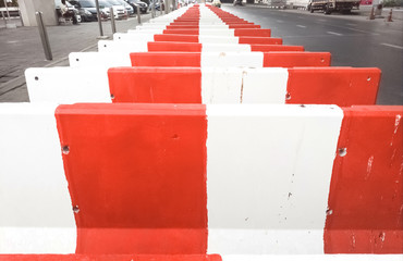 Red and white concrete barriers prepared for blocking the road