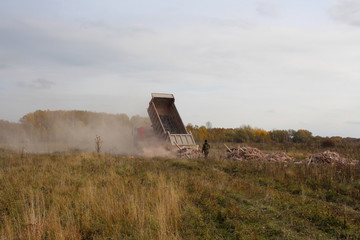 Fototapeta premium the truck dumps debris from the body of construction debris in the field violates the law harms the environment people watching
