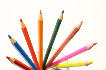 Color pencils inside a glass jar, brown, pink, yellow, purple, green, brown, violet, red, blue, orange, dark green.