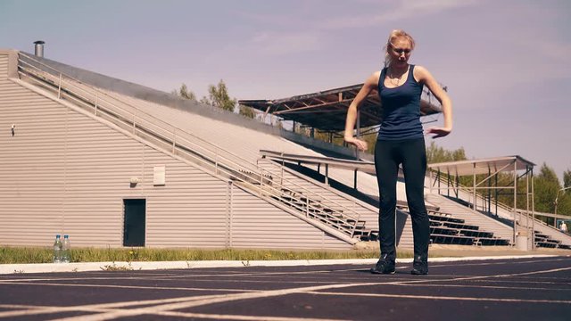 Young cute girl, sporty physique, at stadium. She does the warm-up, before training.