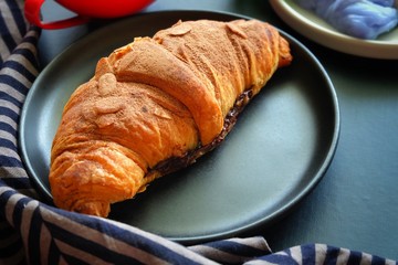 Close up of croissant on black plate.