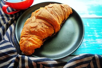 Close up of croissant on black plate.