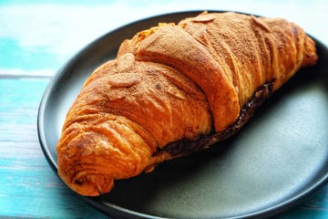 Close up of croissant on black plate.
