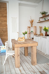 Summer kitchen interior in rustic style. Bright kitchen with a wooden table. Spring flowers and bread in a basket on the table in the kitchen